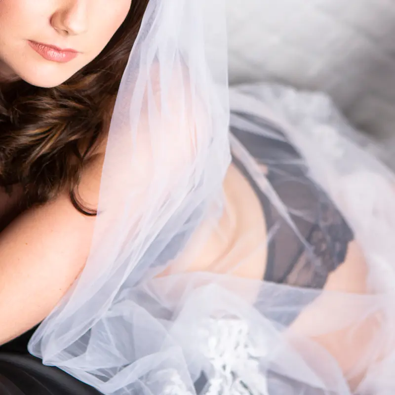 Bride laying on her front using her veil to cover her body.